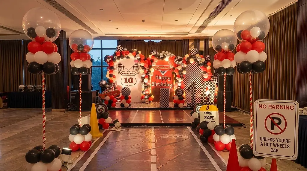 Banquet hall laid out as a racetrack with a painted track floor runner, clear bubble balloon columns and themed signage at a 10th birthday in Lake Town, Kolkata