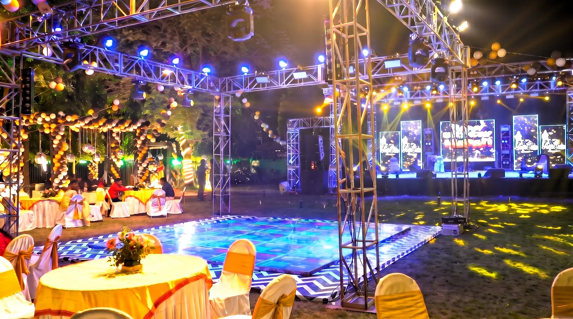 Open-lawn setup with an illuminated LED dance floor, overhead truss lighting, balloon canopy and laid guest tables at a 40th birthday at Elysian Lawn, Salt Lake, Kolkata